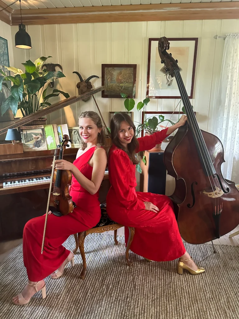 Two women in red dresses playing violin and contrabass at a wedding