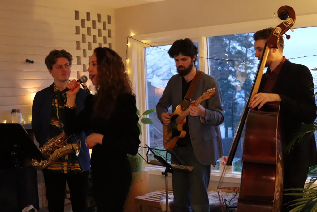 A band with instruments and a lead singer performing at a small home event.