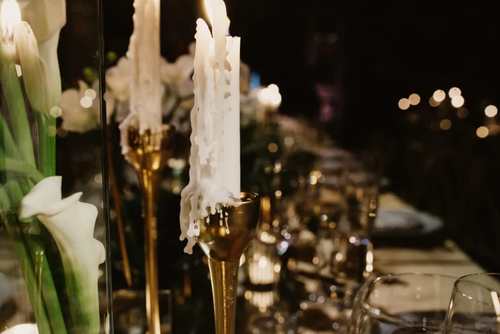 A candle in a golden candlestick on a beautifully decorated memorial table.