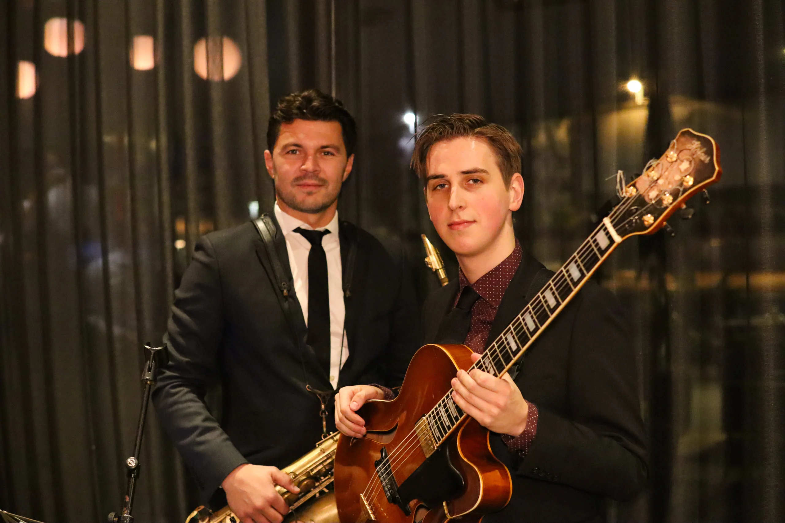 A duo band with a guitarist and saxophonist performing at a private event.