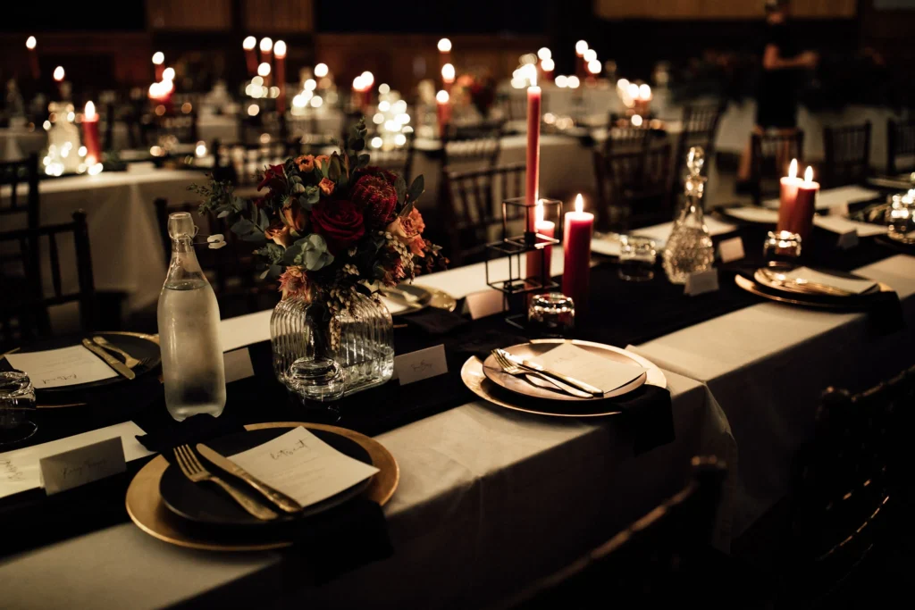 Elegant wedding table setup with luxury decor, including white tablecloths, floral centerpieces, and fine china in an outdoor setting.