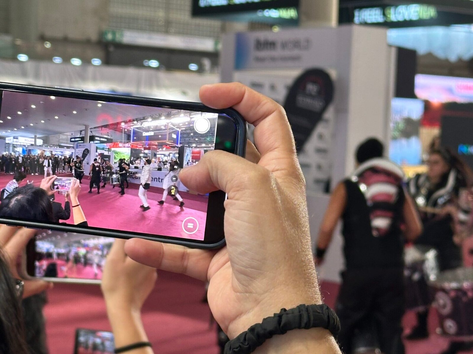 Asistentes grabando una actuación en vivo durante una activación en una feria internacional.